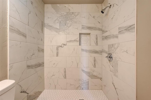 bathroom featuring a tile shower and toilet