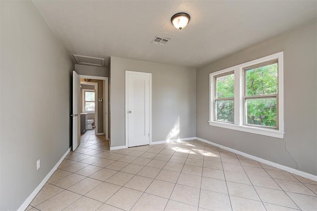 spare room featuring light tile patterned floors and a healthy amount of sunlight