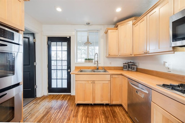 kitchen featuring hanging light fixtures, appliances with stainless steel finishes, sink, and light brown cabinetry