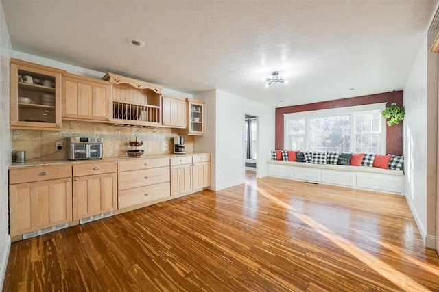 kitchen featuring light brown cabinetry, light wood-type flooring, a textured ceiling, and backsplash