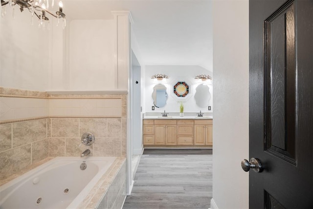 bathroom featuring vanity, tiled tub, and wood-type flooring