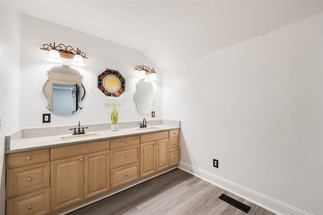 bathroom featuring wood-type flooring, vaulted ceiling, and vanity