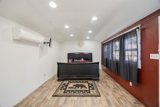 bedroom featuring vaulted ceiling, light hardwood / wood-style floors, and a wall mounted AC