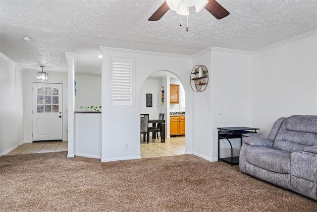 carpeted living room with ceiling fan, a textured ceiling, and ornamental molding