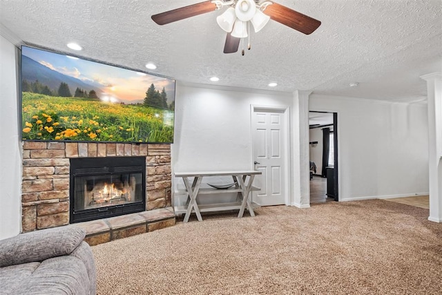 living room with a textured ceiling, ceiling fan, crown molding, a fireplace, and carpet floors