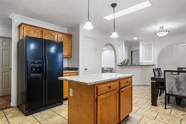 kitchen featuring black fridge with ice dispenser, a textured ceiling, crown molding, a center island, and hanging light fixtures