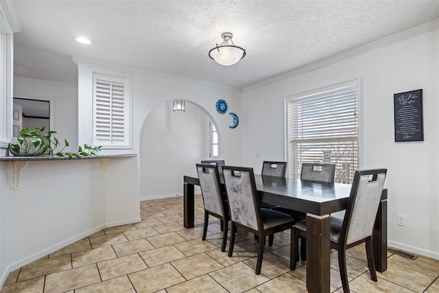 tiled dining space featuring a textured ceiling and crown molding