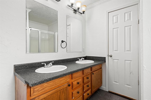 bathroom with vanity, a textured ceiling, a shower with shower door, and ornamental molding