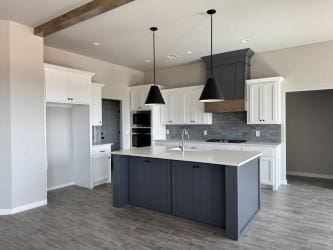 kitchen featuring backsplash, beam ceiling, hanging light fixtures, white cabinetry, and a sink