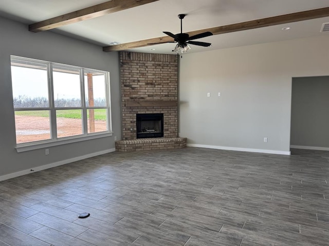 unfurnished living room with beam ceiling, a brick fireplace, baseboards, and wood tiled floor