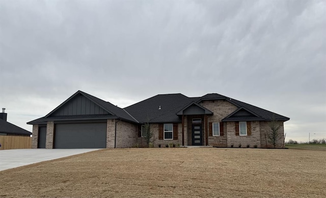 view of front of property featuring a front yard, driveway, a garage, board and batten siding, and brick siding