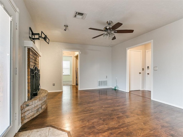 unfurnished living room with ceiling fan, dark hardwood / wood-style floors, and a brick fireplace