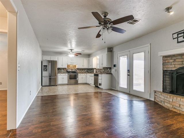 unfurnished living room with a fireplace, a textured ceiling, light hardwood / wood-style floors, and ceiling fan