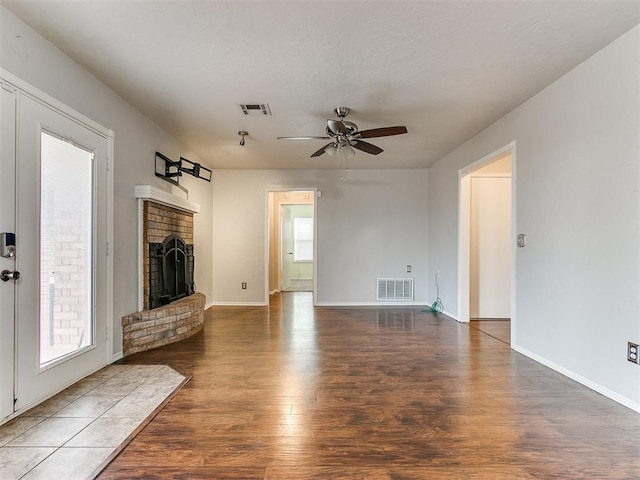 unfurnished living room with dark hardwood / wood-style flooring, a brick fireplace, and ceiling fan