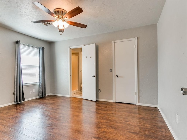 spare room with a textured ceiling, ceiling fan, and dark wood-type flooring