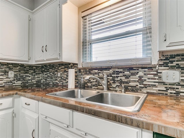 kitchen featuring decorative backsplash, a healthy amount of sunlight, white cabinetry, and sink