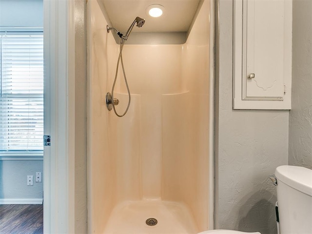 bathroom featuring a shower, hardwood / wood-style floors, and toilet