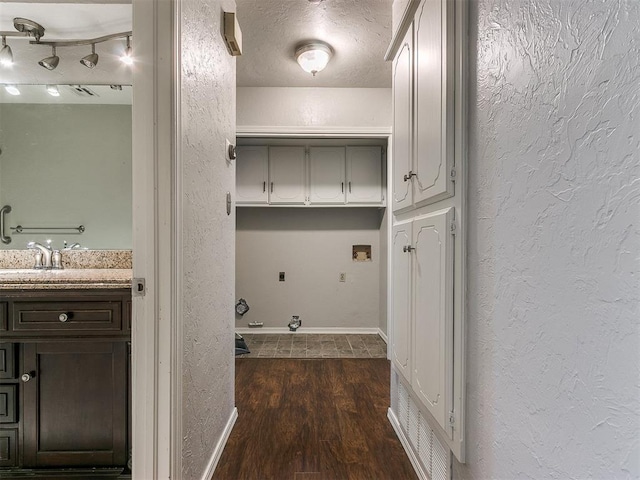 washroom featuring a textured ceiling, sink, electric dryer hookup, and dark hardwood / wood-style floors