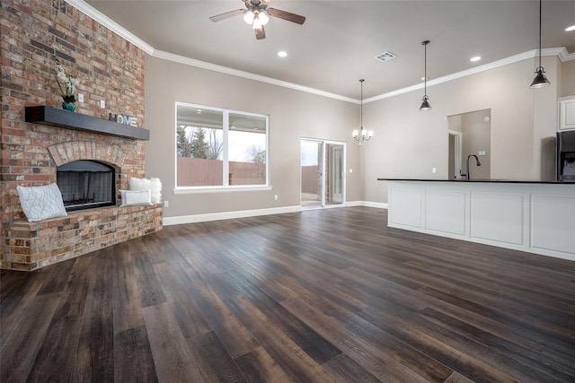 unfurnished living room featuring dark hardwood / wood-style flooring, ornamental molding, sink, and a fireplace