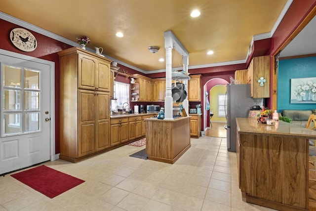 kitchen with sink, appliances with stainless steel finishes, ornamental molding, a kitchen island, and kitchen peninsula