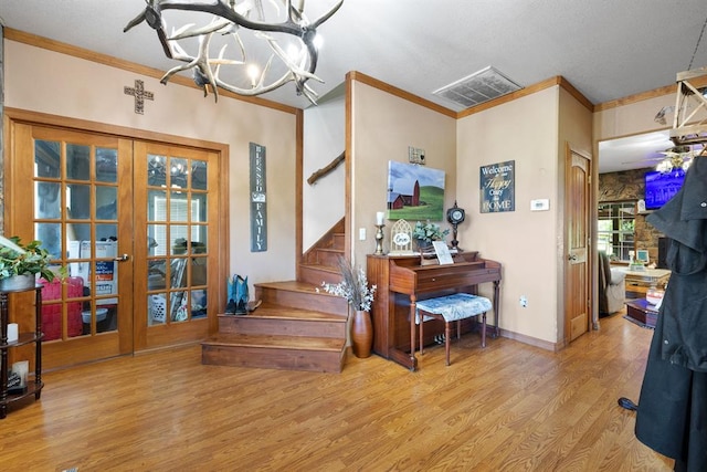 entrance foyer with a notable chandelier, light hardwood / wood-style flooring, ornamental molding, and french doors