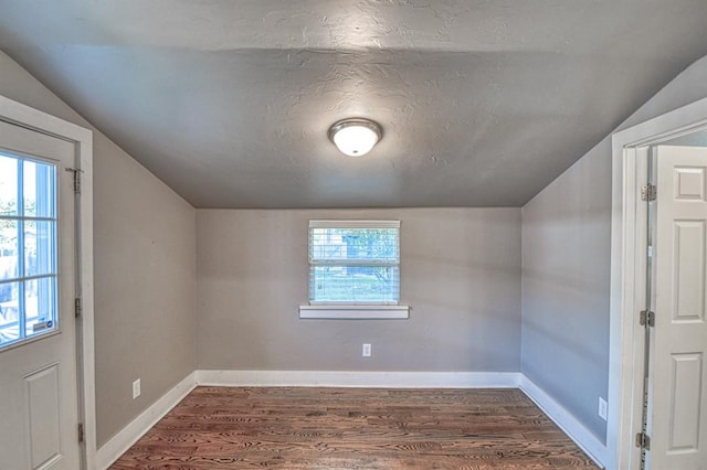 additional living space with a textured ceiling, dark hardwood / wood-style flooring, and lofted ceiling