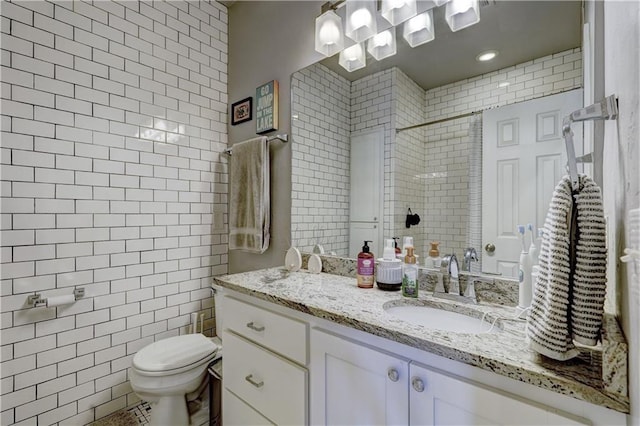 bathroom with vanity, toilet, a shower, and tile walls