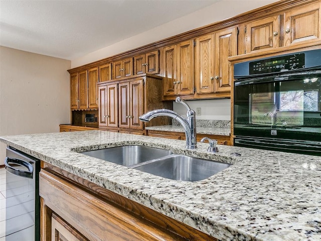 kitchen with light stone countertops, dishwasher, sink, tile patterned floors, and black double oven