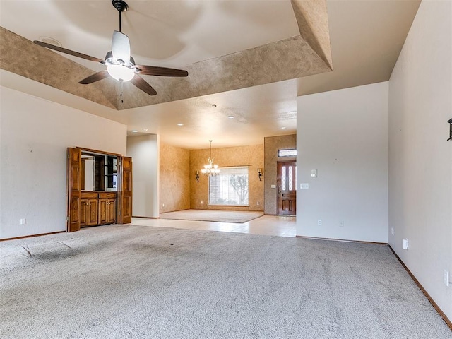 unfurnished living room with ceiling fan with notable chandelier, light colored carpet, and a raised ceiling