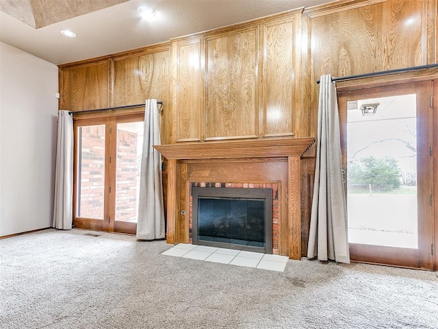 unfurnished living room with a tile fireplace and light colored carpet