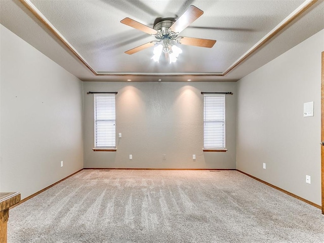 carpeted spare room featuring a tray ceiling and ceiling fan