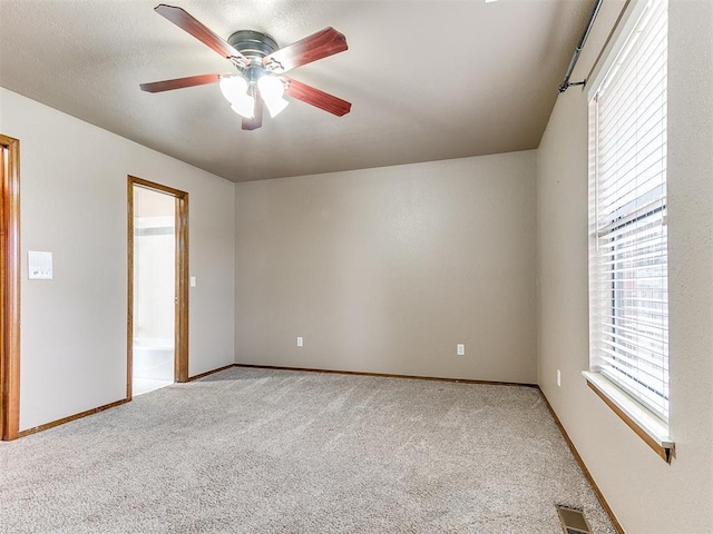 carpeted empty room featuring a wealth of natural light and ceiling fan