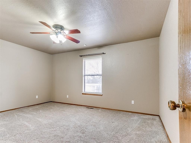 empty room with ceiling fan, light colored carpet, and a textured ceiling