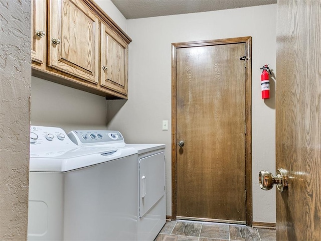 washroom featuring cabinets, a textured ceiling, and washing machine and clothes dryer