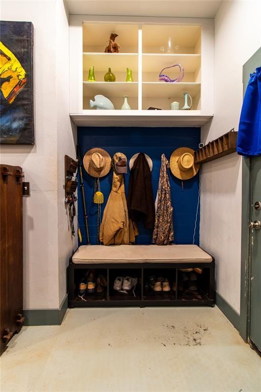 mudroom with built in shelves and concrete flooring