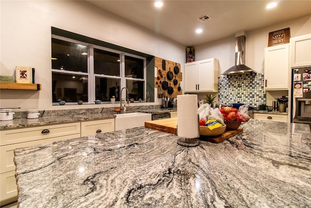 kitchen with white cabinetry, wall chimney range hood, and sink