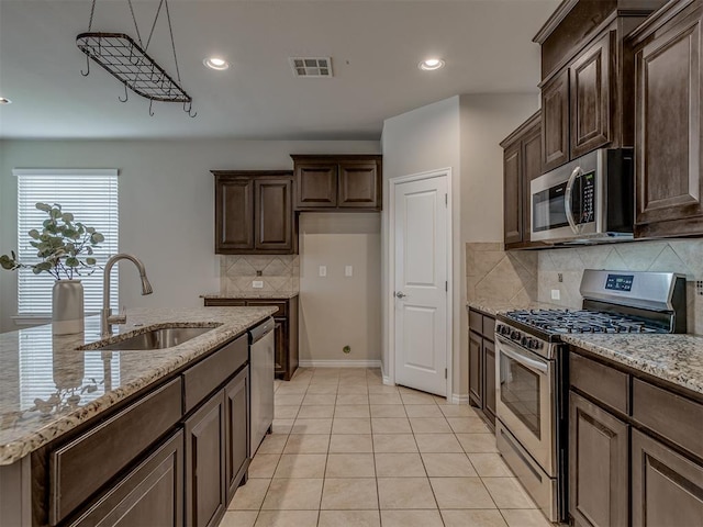 kitchen featuring backsplash, light stone countertops, sink, and appliances with stainless steel finishes