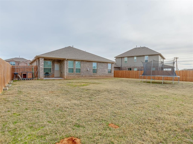 rear view of house with a trampoline and a yard