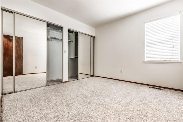 unfurnished bedroom featuring carpet and two closets