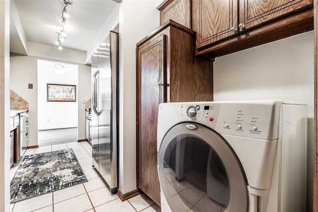 clothes washing area with washer / dryer and light tile patterned floors