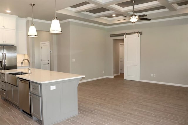 kitchen featuring coffered ceiling, pendant lighting, a barn door, a center island with sink, and dishwasher