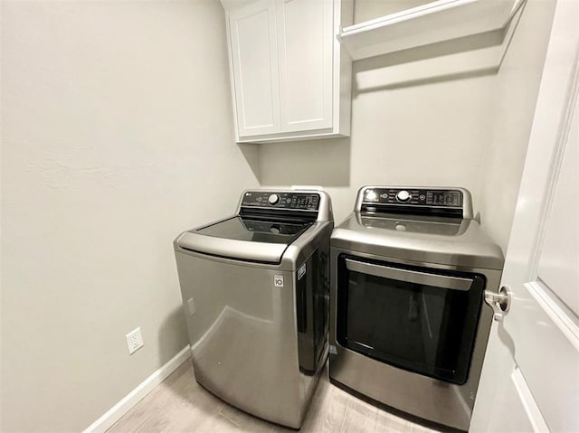 clothes washing area featuring washer and dryer, cabinets, and light hardwood / wood-style flooring