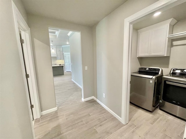 laundry area featuring cabinets, independent washer and dryer, and light hardwood / wood-style flooring