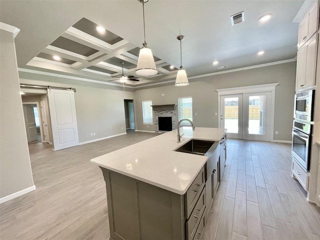 kitchen with a barn door, pendant lighting, stainless steel appliances, and light wood-type flooring