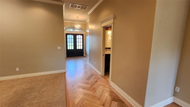 hallway with crown molding, french doors, parquet floors, and an inviting chandelier