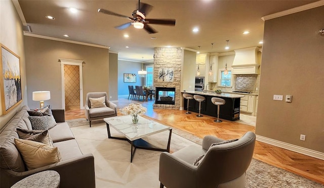 living room featuring light parquet flooring, a stone fireplace, ceiling fan, and ornamental molding