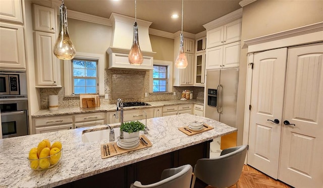 kitchen with sink, hanging light fixtures, decorative backsplash, light stone countertops, and appliances with stainless steel finishes