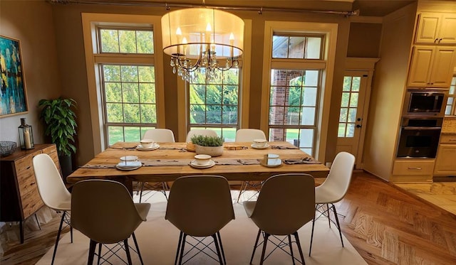 dining area with light parquet floors and an inviting chandelier