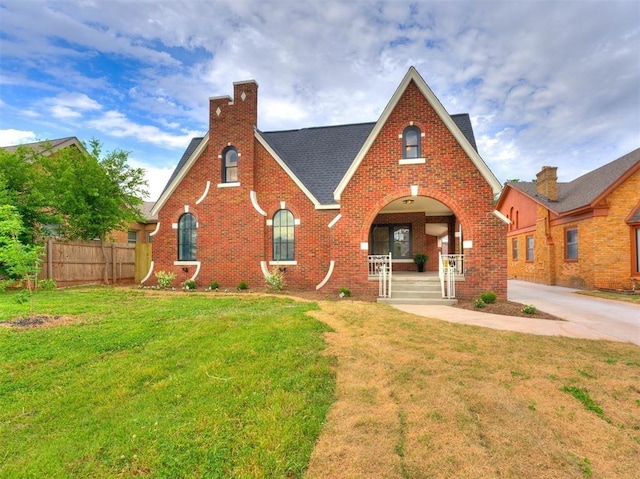 tudor-style house with covered porch and a front lawn