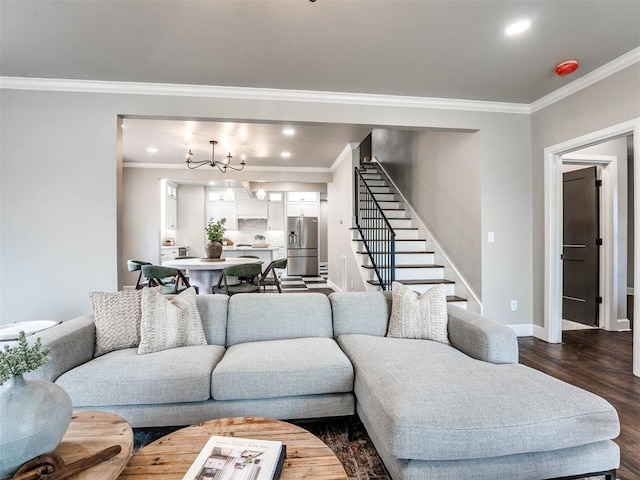 living room with dark hardwood / wood-style flooring, ornamental molding, and an inviting chandelier